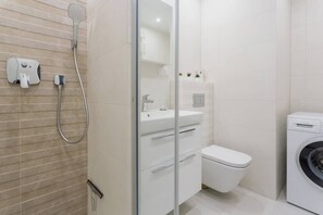 Bright bathroom with washing machine and shower cabin. 