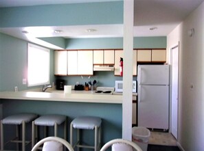 Fully- equipped kitchen and dining area with table for six and extra bar seating