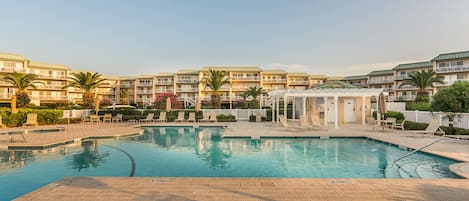 Pool area with outdoor tables, chairs, loungers, and table umbrellas