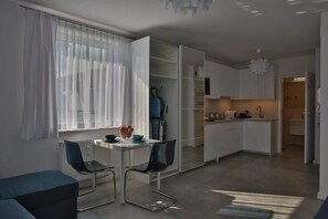 Another view of the studio living space, featuring a small round dining table with chairs, perfect for a cozy meal or workspace.