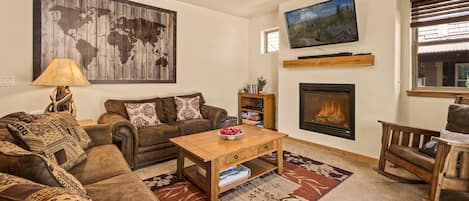 Living room has big comfy couches with Cable TV, sound bar and gas fireplace.