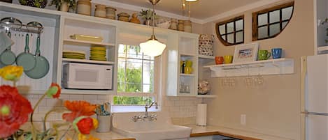 Bright charming coastal kitchen with farm sink. Antique windows over shelf.