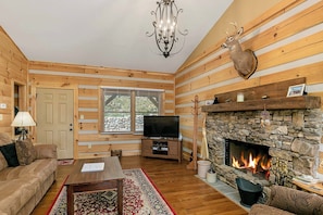 The living room boasts cozy furnishings, a TV, and a fireplace.