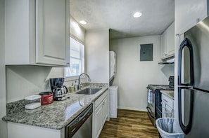 The kitchen has stainless steel appliances - fridge, dishwasher, stove/oven. 