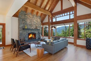 Formal seating area features vaulted ceilings, a wood-burning fireplace, and scenic vistas