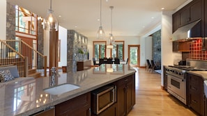 Contemporary gourmet kitchen with stainless steel appliances, a gas range, and a wine fridge