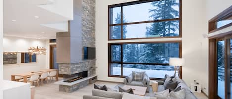 Open plan living area with vaulted ceiling and towering windows