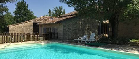 View across pool with farmhouse behind.