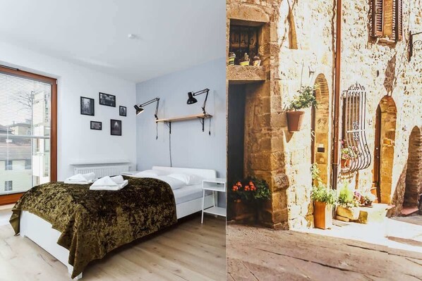 A bright bedroom space with a double bed on which lies a dark green bedspread.