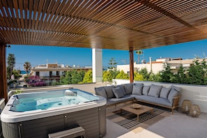 Shaded veranda on the first floor, featuring a hot tub, ping pong table & sofa.