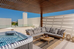 Shaded veranda on the first floor, featuring a hot tub, ping pong table & sofa.