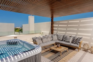 Shaded veranda on the first floor, featuring a hot tub, ping pong table & sofa.