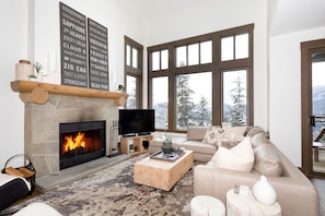 Large open concept living room with fireplace and large bay windows