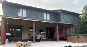 large covered patio in back yard including propane fire pit, grill and hot tub