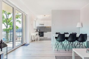 Spacious dining area with a large table and black chairs. The open layout leads into the living space with a view of the balcony.