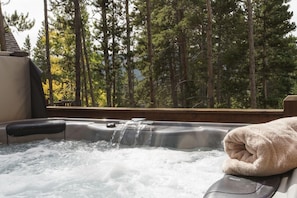 Bubbling hot tub overlooking forest views and the mountains.