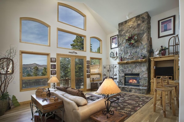 View of the family room with gas fireplace, flat screen television, balcony, and open floor plan for hosting larger groups