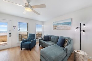 Living area with new furniture, flooring throughout and a beautiful view of the beach from the large windows