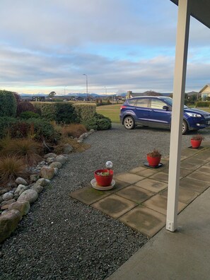 front of the house with large grass reserve behind the car
