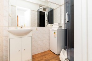 Bright bathroom with washing machine and shower cabin. 