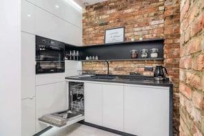 Kitchenette with dishwasher, kettle, stove, sink, oven and cupboards