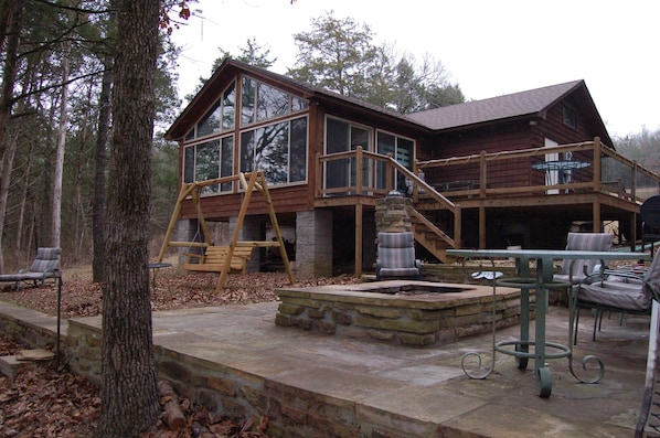 Rock patio with fire pit is just below the deck. 