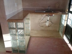 kitchenette with sink/counter/burner stove and french press. 