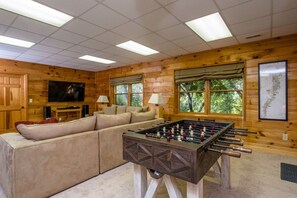 Living room on the lower level of the home. Features a smart TV, and foosball.