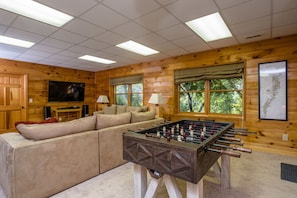 Living room on the lower level of the home. Features a smart TV, and foosball.