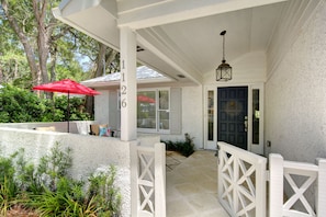 Front Porch Charm • Shaded Entry • St. Simons Island - Welcome to Sea Glass Cottage. This shaded front porch is the perfect entry point—framed by cottage-style railing, lush landscaping, and a quiet island vibe. It’s the kind of door you’ll be happy to come home to after beach days and dinner at Crab Daddy’s.