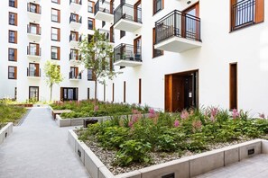 This picture captures the exterior view of a modern apartment building, with well-maintained landscaping and pathways around the building.