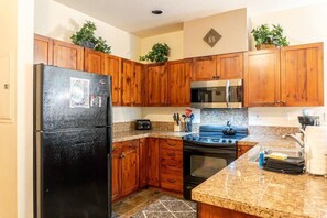 The efficient and fully-equipped kitchen boasts tile floors, stone counters and abundant cabinet space as well as a bar with seating for two.