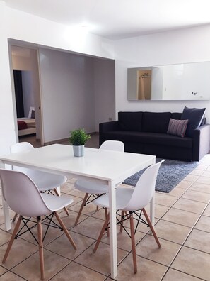 Area de comedor con 4 sillas, smart TV y esta proximo al area de cocina.