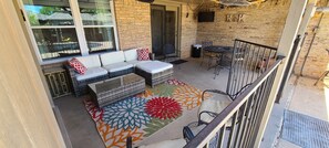 large covered patio, with couch, table, and tv overlooking pool