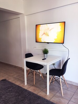 Area de comedor con 2 sillas, smart TV y esta proximo al area de cocina.