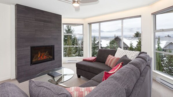 Spacious and bright living area with fireplace, mountain views and TV