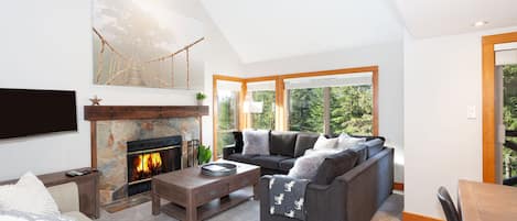 Large picture windows offer an abundance of natural light and scenic views of the forest and mountain