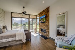 Master Bedroom with a King Bed, Stone Wall with a Gas Fireplace and 55" Smart TV, and Plenty of Natural Light