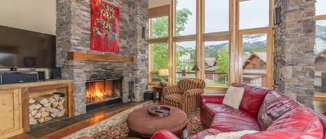 Grand living room with TV, wood burning fireplace, amazing views