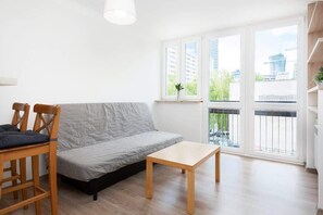A cozy corner with a compact sofa and small table, perfect for relaxing or watching TV in the main studio space.