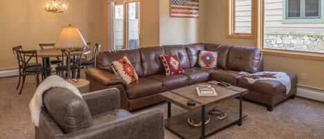 Open concept downstairs living area with roomy leather sectional and armchair