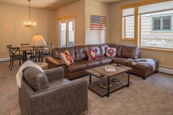 Open concept downstairs living area with roomy leather sectional and armchair