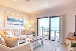 Cozy living room with a beachside balcony, soft lighting, and coastal decor.