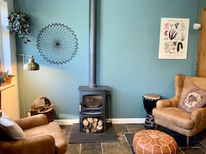 The kitchen includes a log burner and armchairs for added comfort.