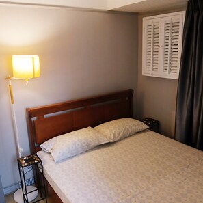 The bedroom with queen size bed and a cabinet with hanging rack.