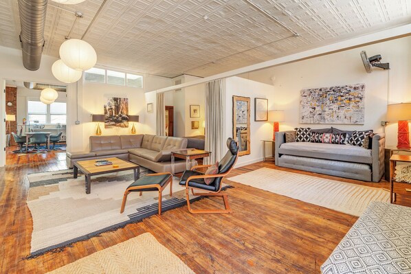 Just inside the entrance of  33 Carolina Lane Loft's main living area with 60" wall mounted tv, adjacent to the second king bed, separated by custom drapes for privacy. Other king bed is in a separate bedroom, just off the dining area. 