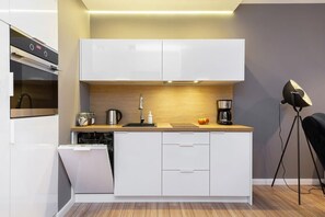 A modern, white kitchen with glossy cabinets, wooden accents, and under-cabinet lighting, creating a functional and stylish cooking area.