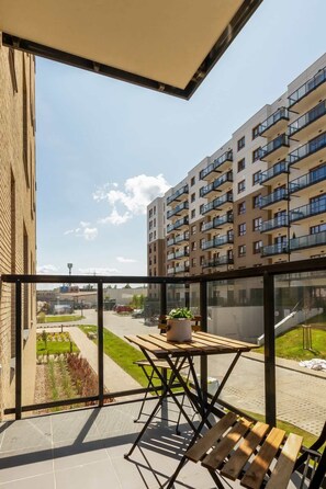 A balcony featuring outdoor furniture, including chairs and a table. The view includes neighboring buildings, and the space is perfect for relaxation.