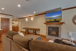 Living area with comfy sectional sofa, flat screen tv, fireplace, and shuffleboard