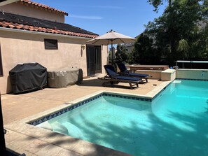 large outdoor table with chairs under tan cover.
